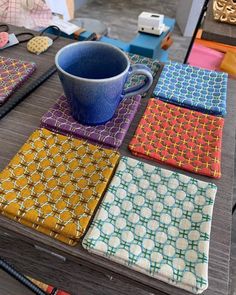 a table topped with different colored cloths and a blue cup on top of it