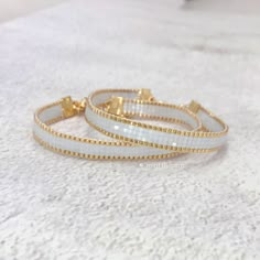 two white and gold bracelets sitting on top of a table