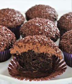 chocolate cupcakes on a plate with one cut in half to show the inside