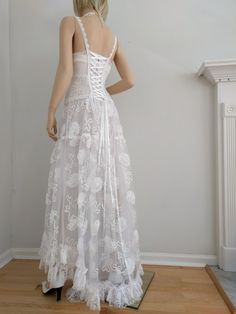 the back of a woman's wedding dress is shown in front of a white wall