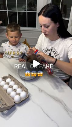 a woman and boy sitting at a table with eggs