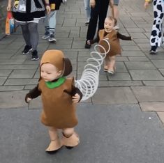 a little boy in a monkey costume is holding onto a wire fence while walking down the street