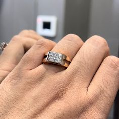 a person's hand with a ring on top of their finger and an electronic device in the background