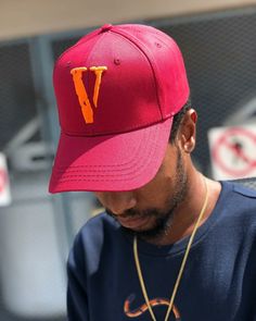 a man wearing a red hat with the letter v on it looking at his cell phone