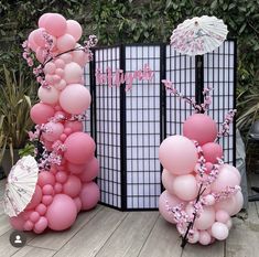 balloons and umbrellas are arranged on the ground near a fence with trees in the background