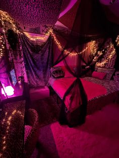 a bedroom decorated in purple and leopard print with lights on the ceiling, bed canopy and chair