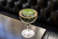 a glass filled with liquid sitting on top of a table next to a black couch