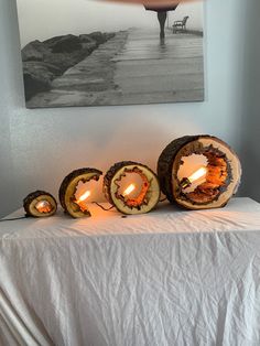 some logs are sitting on a table with candles in front of them and a painting hanging above it