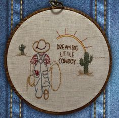 the embroidery is on and there is a small boy in overalls with a cowboy hat