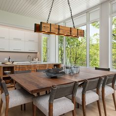 a dining room table and chairs in front of large windows