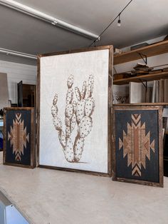 three framed art pieces sitting on top of a counter next to each other in a room