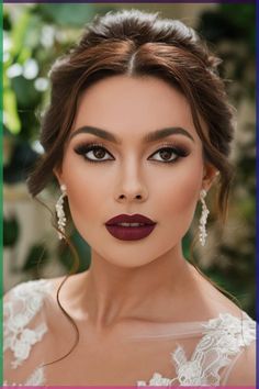 This bridal makeup look features striking deep red lipstick paired with defined brows and a soft smokey eye. The delicate earrings add a touch of elegance, complementing the bride's flawless complexion and updo. A perfect combination of sophistication and modern glamour. Makeup To Match A Red Dress, Bridal Makeup With Dark Lips, Eye Makeup With Wine Dress, Wine Lip Makeup Look, Sultry Makeup Tutorial Step By Step, Bridesmaid Makeup Dark Lip, Natural Wedding Makeup Red Lips, Holiday Makeup Red Lips, Hollywood Bridal Makeup