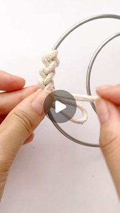 two hands are tying a rope around a circular object