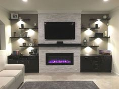 a living room with a couch, fireplace and entertainment center in the middle of it