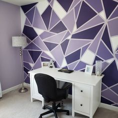 a desk with a computer on it in front of a purple and white geometric wall