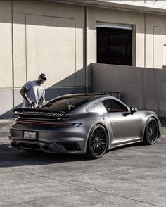 a man standing on top of a gray sports car