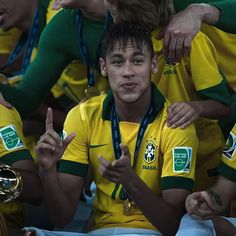 a group of young men sitting next to each other in front of a trophy and giving the thumbs up sign