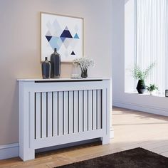 a white radiator sitting on top of a wooden floor next to a window