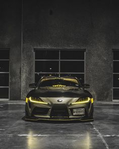 the front end of a sports car parked in a parking lot with its lights on