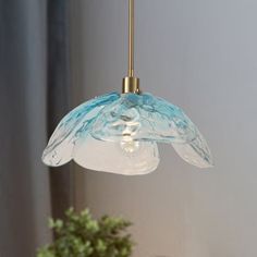 a blue and white glass light hanging from a gold colored ceiling fixture in a living room