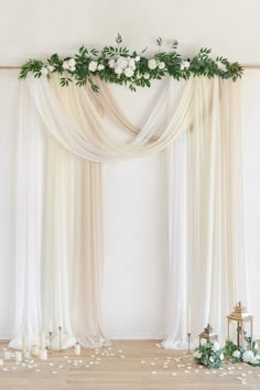 the wedding arch is decorated with greenery and white flowers for an elegant touch to the room