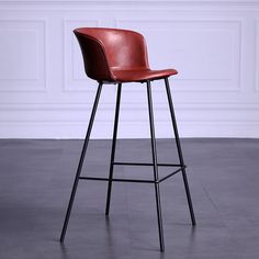 a brown leather bar stool sitting on top of a black metal frame floor next to a white wall