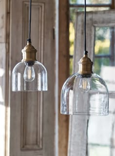 two clear glass pendant lights hanging from a ceiling