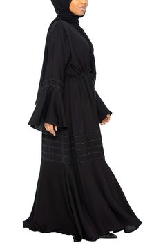 Add a touch of style with our beautiful Suhayla Abaya in Classic Black. This umbrella-cut abaya offers a wide sweep for a graceful, elegant flow. With elegant stonework adorning the sleeves and peplum, this gorgeous piece will have you looking absolutely amazing. Made with silky Nida Open abaya with hidden buttons A-line cut for a modest fit Model is 5'5 and is wearing a size 56 Includes a matching scarf Honey Dip Scarf in Classic Black (shown above) sold separately Made in Dubai Honey Dip, Open Abaya, Modest Fits, City Girl, In Dubai, Nun Dress, Classic Black, Apparel Accessories, Dip