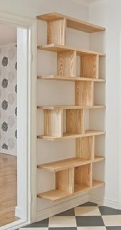 an empty bookcase in the corner of a room with black and white checkered flooring