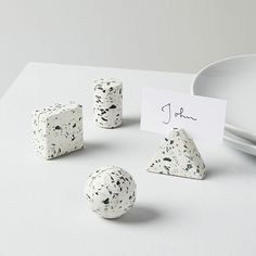 three dices and two pieces of paper on a white surface with a place card