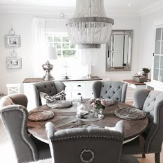 the dining room table is set for four with gray upholstered chairs and silver accents