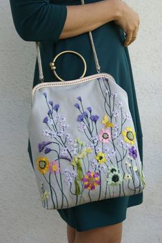 a woman holding a purse with flowers painted on it