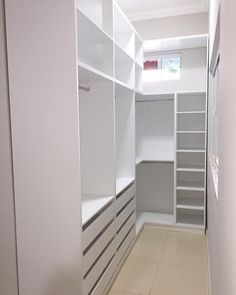 an empty walk in closet with white shelves