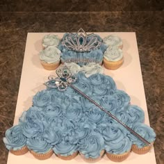 a princess dress made out of cupcakes on top of a white sheet with blue frosting