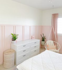 a bedroom with pink walls and white furniture