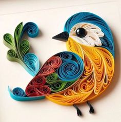 a colorful bird made out of paper sitting on top of a white table next to scissors