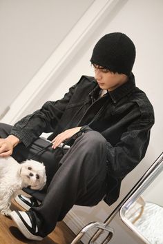 a man sitting on top of a wooden floor next to a white dog