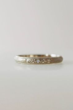 a white gold wedding ring with three diamonds on it's side, sitting on a table