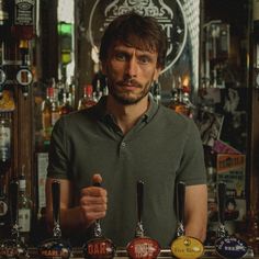 a man standing in front of a bar filled with beer taps