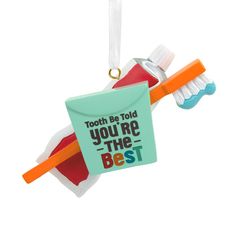 toothbrush and toothpaste shaped ornament hanging from a string on a white background