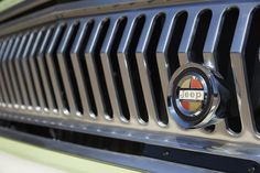 the front grille of a green car with a jeep emblem on it's grill