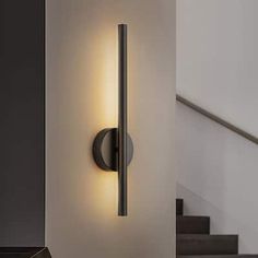 a wall light that is mounted on the side of a wall next to some stairs