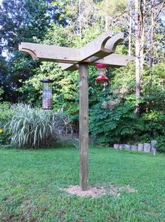 a wooden bird feeder in the middle of a yard