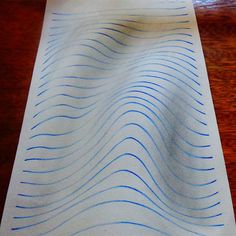 a piece of paper with blue lines on it sitting on a wooden table next to a cell phone