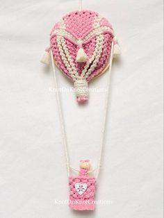 a pink and white crocheted purse with chain attached to it