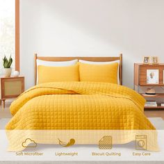 a bed with yellow comforter and pillows on it