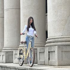 a woman standing next to a bike in front of columns