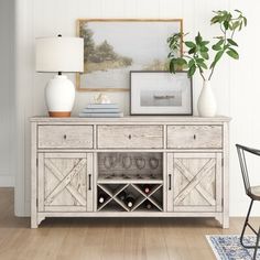 a white sideboard with wine glasses on it and a lamp next to it in a living room