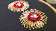 two gold and red brooches sitting on top of a black cloth