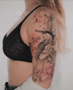 a woman's arm with a bird and flowers tattoo on her left side shoulder